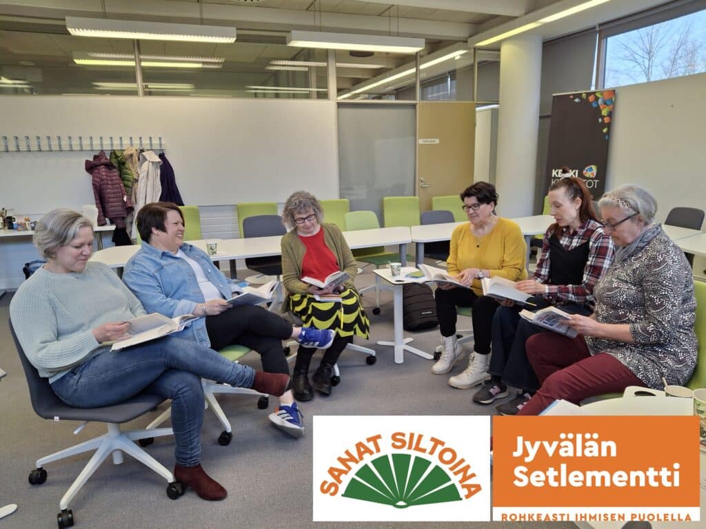 Ihmisen istumassa piirissä toimistotilassa kirjat kädessään keskustelemassa kirjoista. Taustalla vihreitä tuoleja ja valkoiset toimistotilat. Kuvan vasenmassa alakulmassa on Jyvälän Setlementin ja Sanat Siltoina -hankkeen logot.